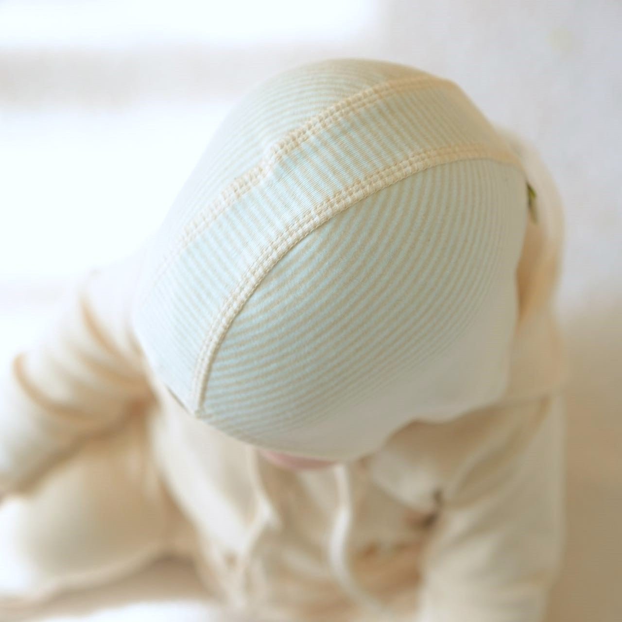 Macro view showing the breathable knit structure of the seamless organic cotton infant skull cap style bonnet