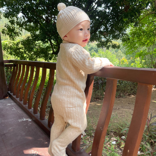 mini-cable organic nature colored baby footed romper and hat set on baby outside in park