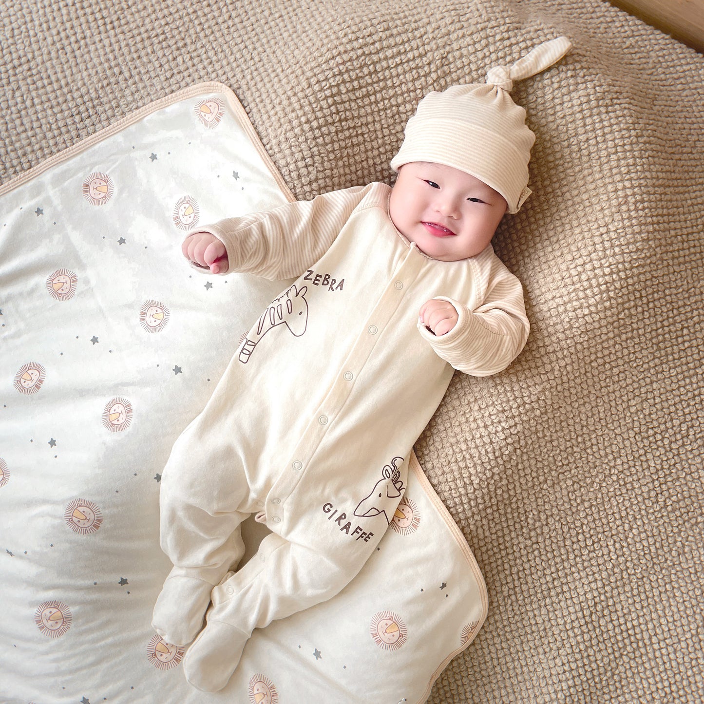 Newborn baby wearing a zebra print sleepsuit in a modern safari-themed nurseryl 
