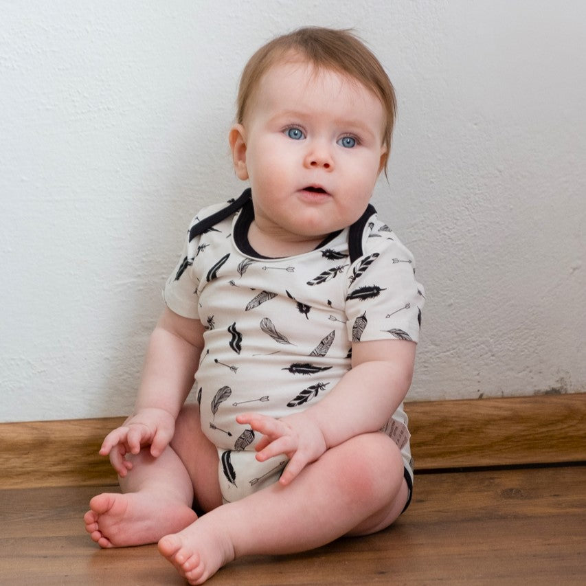 Newborn baby wearing a monochrome feather print organic cotton bodysuit | Eotton Canada