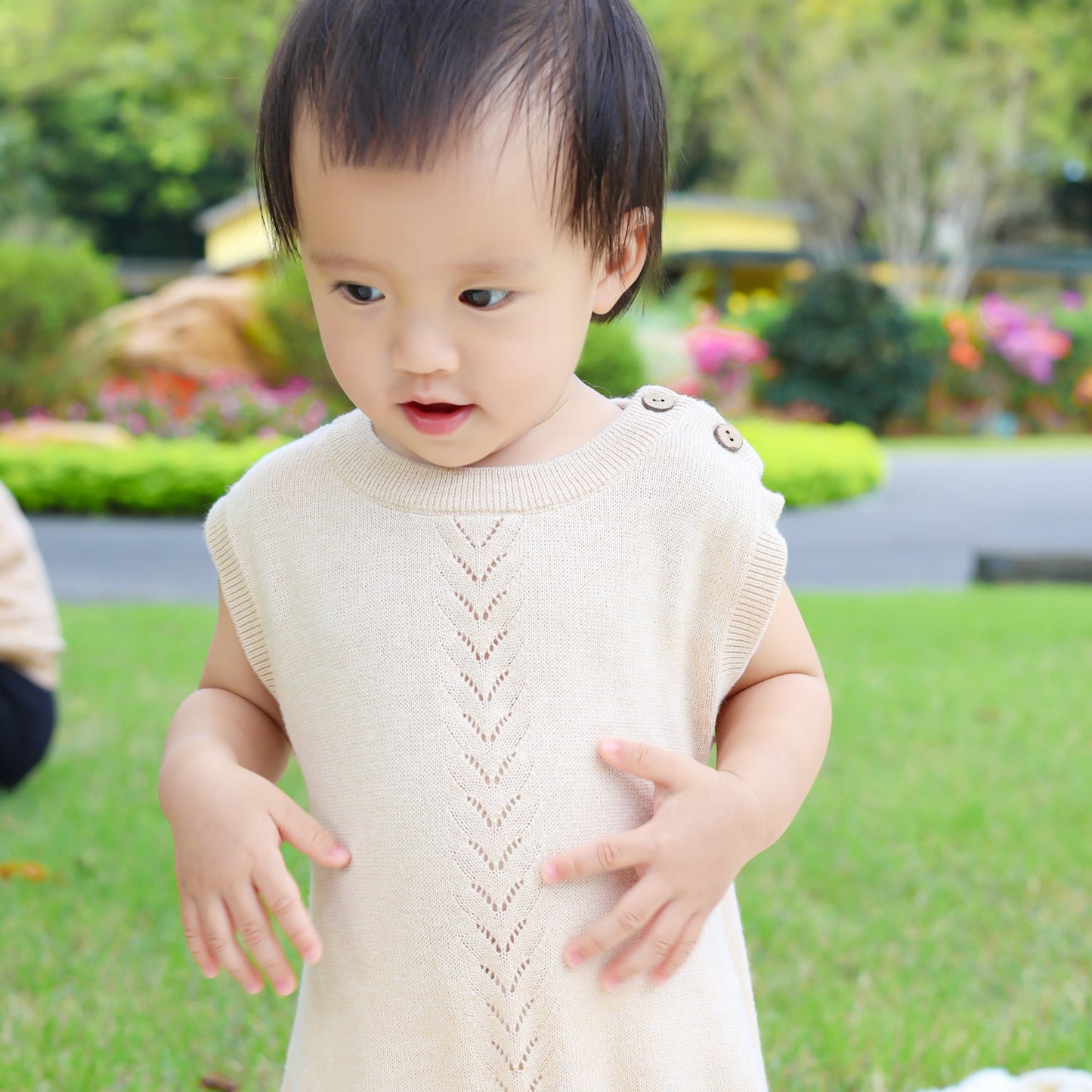 Sleeveless mini-cable baby romper featuring 100% natural coconut shell buttons on shoulders and crotch