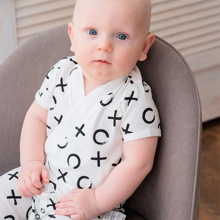 Detailed layout of the durable flat lying bottom snap closures on a short sleeve monochrome infant jumpsuit.