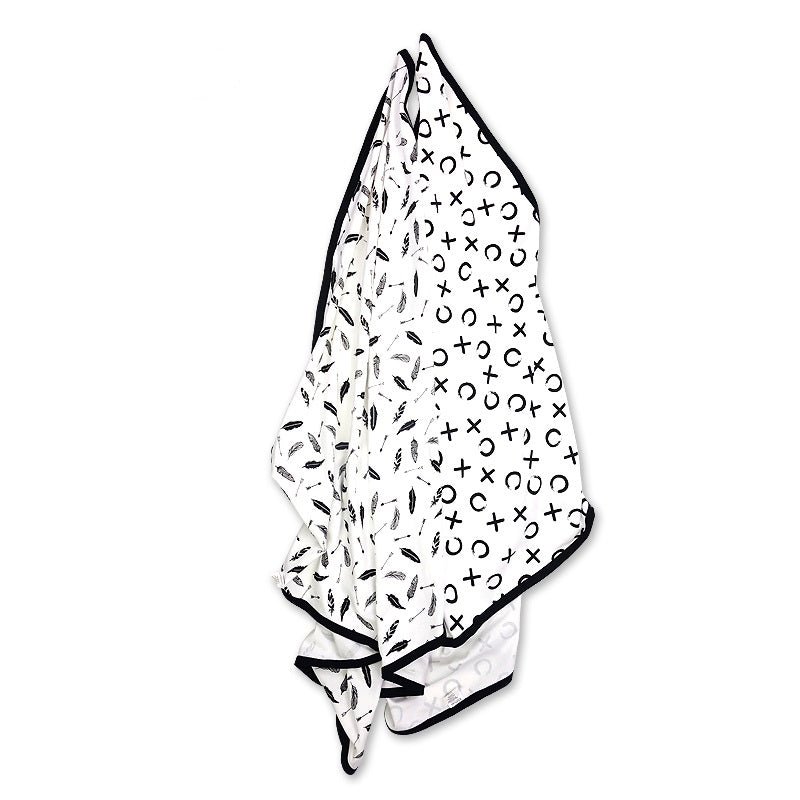 Two silky organic cotton stretch baby blankets with high contrast monochrome patterns hanging neatly against a clean backdrop.
