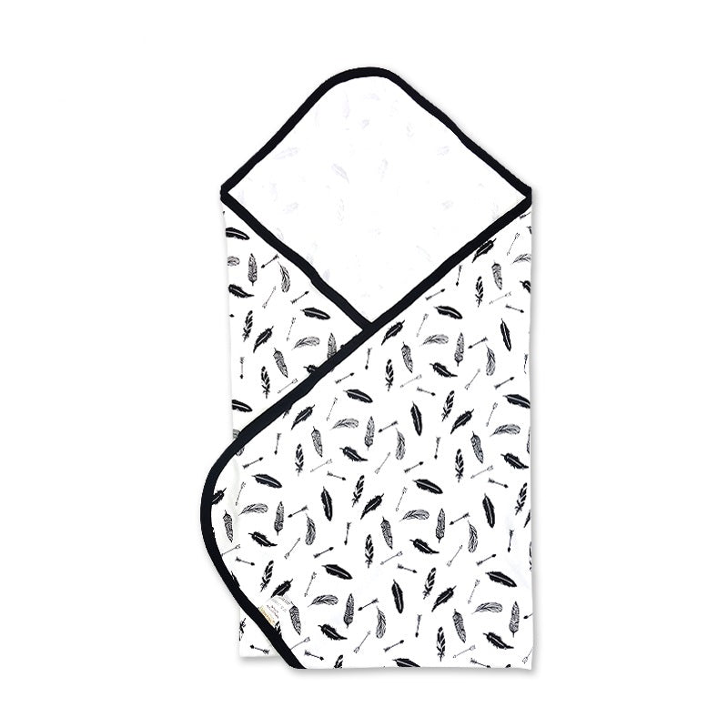 Large square organic baby receiving blanket displaying a high contrast black and white feather pattern folded in a swaddle shape.