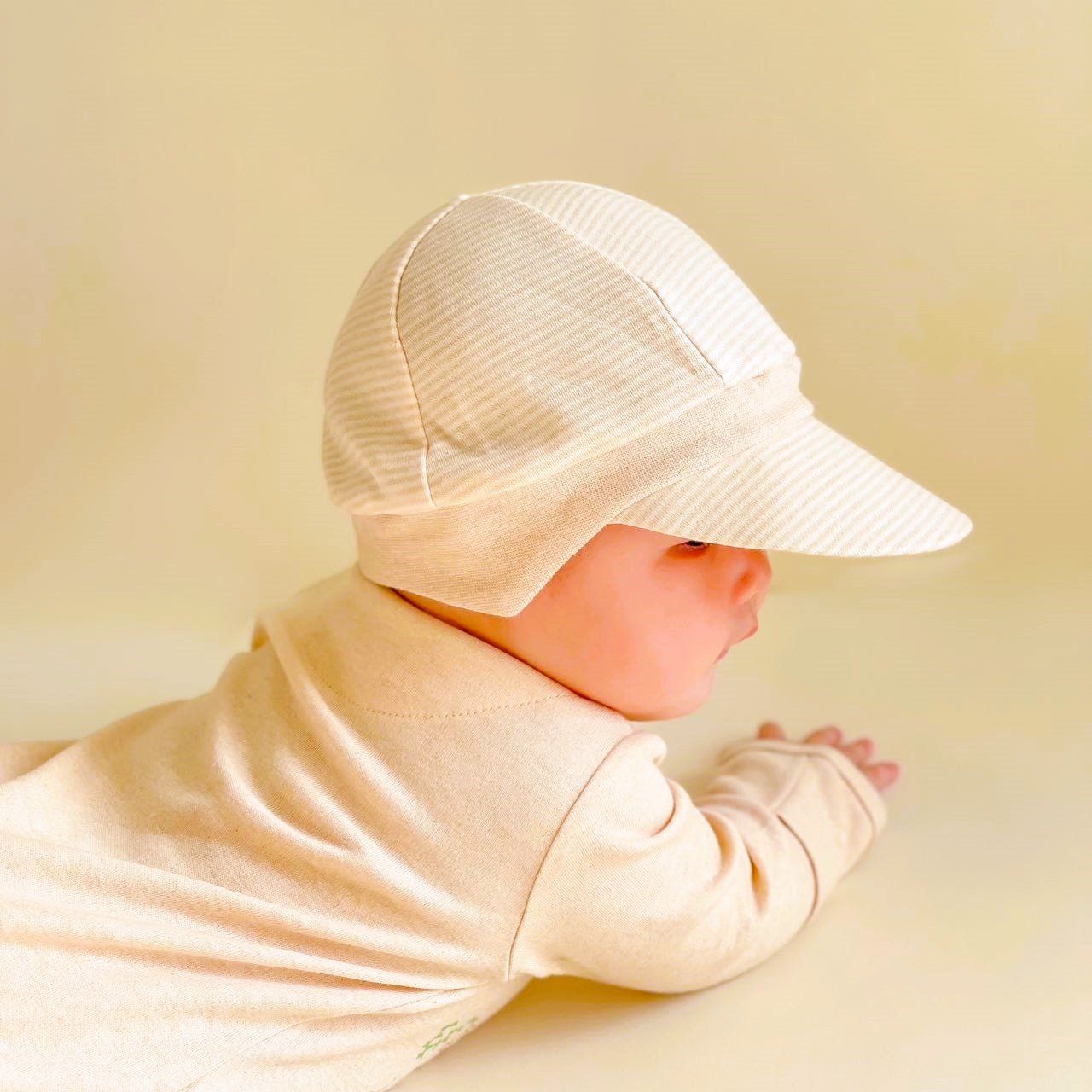 Rear angle view showing the flexible elasticized fit of a chemical free baby sun cap with protective ear panels.