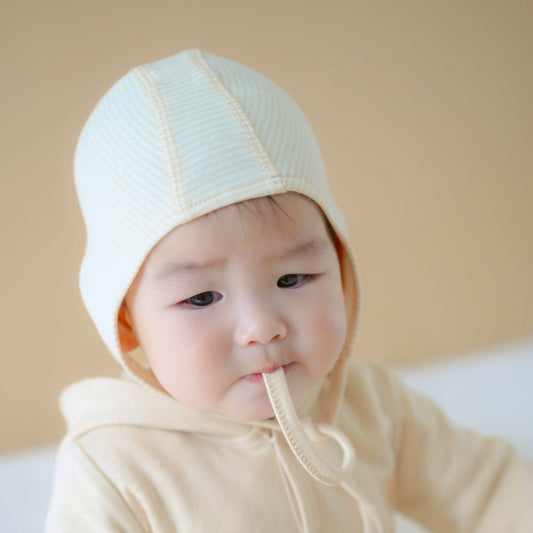Organic cotton baby hats showcasing the classic tie bonnet silhouette in unbleached natural cotton
