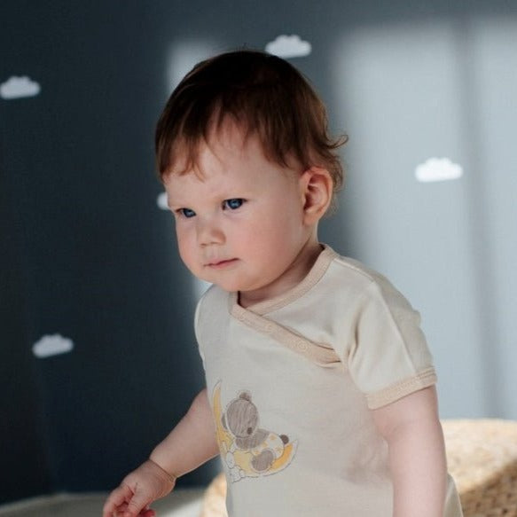 Organic nature colored cotton baby romper and neutral newborn short onesie displayed in a light earthy tan shade
