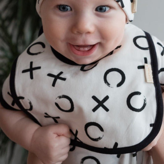 Two pack organic newborn bib set displaying the white feather print and the graphic XOXO design layout.