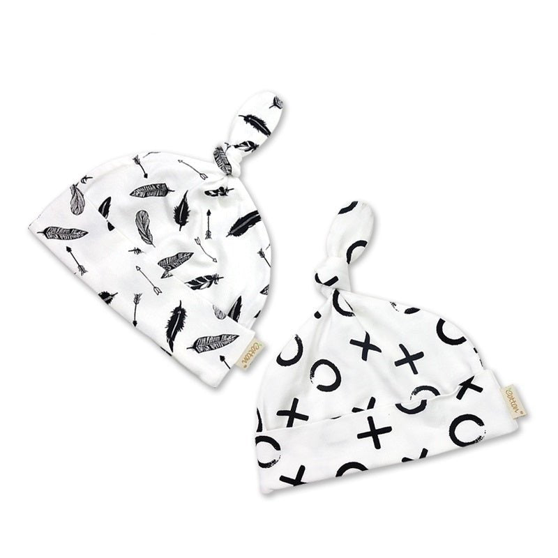 Two piece organic newborn knotted hat set displaying the black feather pattern and the white XO print layout side by side.