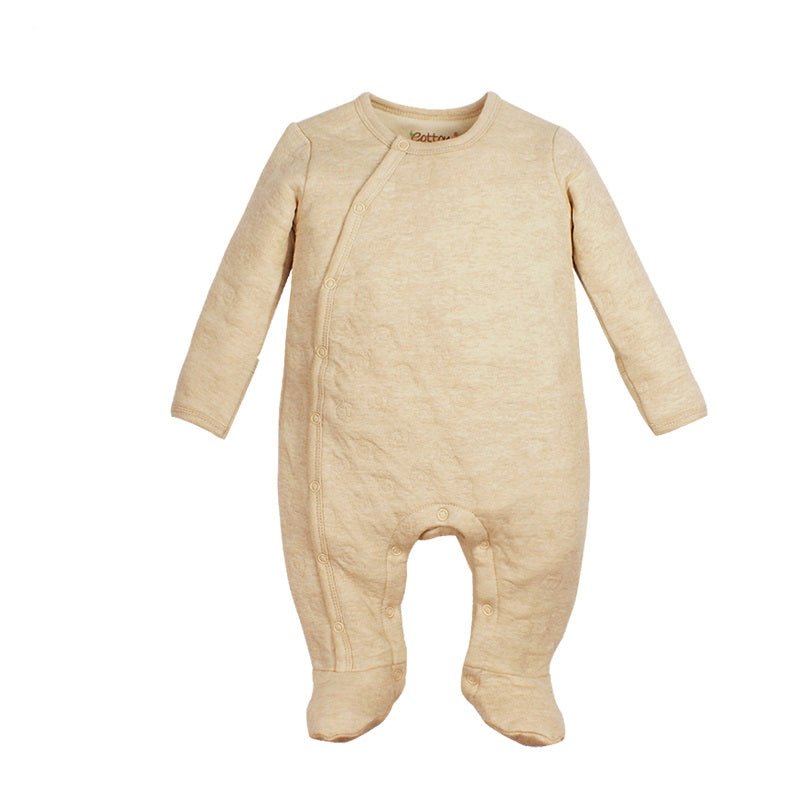 A cozy infant resting in a thick natural cream organic cotton thermal footie romper featuring a three layer airlayer texture with attached booties and mittens