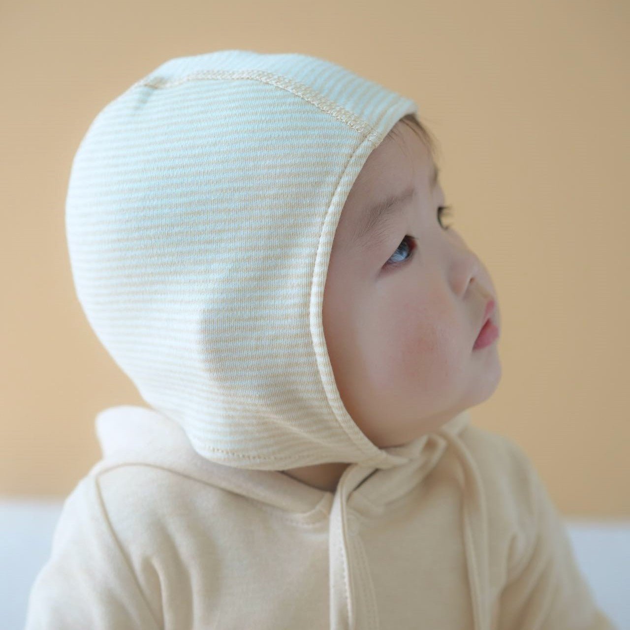 Soft cotton baby caps with adjustable chin ties worn comfortably by an infant