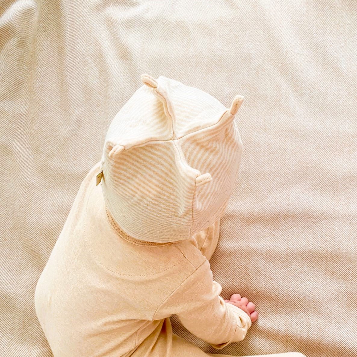 Over the top view of an organic newborn beanie with 4 rope knots on top forming a soft structured crown shape.